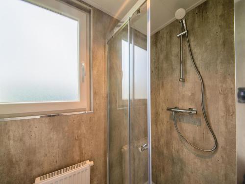 een badkamer met een douche en een glazen deur bij Brand new spacious mobile home with private terrace, next to a babbling brook in Érezée