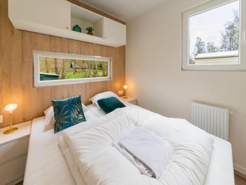 een groot wit bed in een slaapkamer met een raam bij Brand new spacious mobile home with private terrace, next to a babbling brook in Érezée