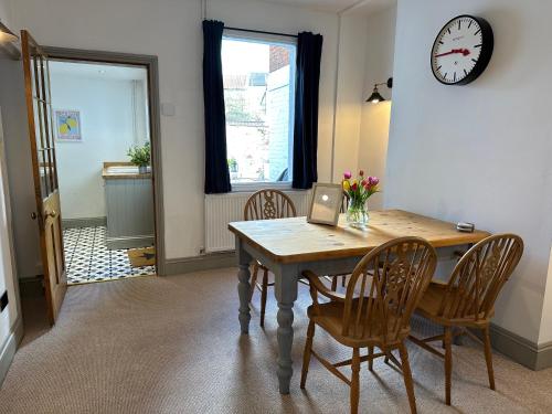 a dining room table with chairs and a clock on the wall at Quayside Georgian Townhouse in Kings Lynn