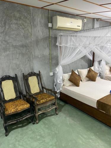 1 Schlafzimmer mit 2 Betten und 2 Stühlen in der Unterkunft Shek villa in Hikkaduwa