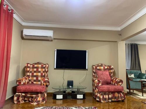 een woonkamer met 2 stoelen en een flatscreen-tv bij Unique location, fully furnished flat in Cairo in Caïro