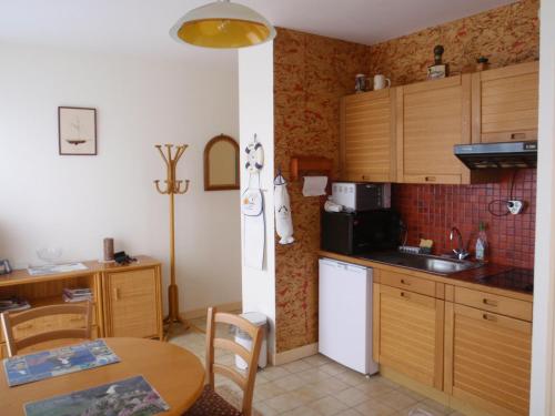 - une cuisine avec des placards en bois, une table et un évier dans l'établissement Studio les pieds dans l'eau au port de Ploumanac'h, à Perros-Guirec