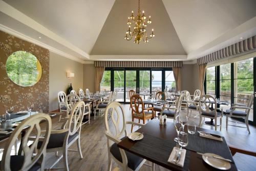 a restaurant with tables and chairs and a chandelier at Hotel La Barcarolle in Prangins