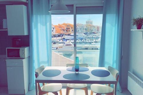 - une table et des chaises dans la cuisine avec vue sur le port dans l'établissement Studio les 5M centre Port Cap d'Agde, au Cap d'Agde