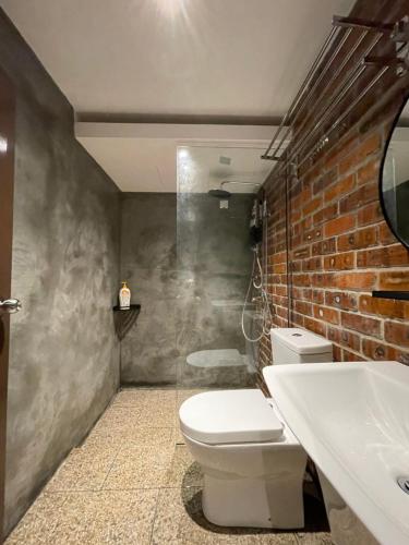 a bathroom with a toilet and a sink and a brick wall at Grand Lodge Langkawi in Pantai Cenang