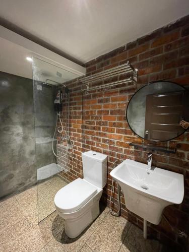 a bathroom with a white toilet and a sink at Grand Lodge Langkawi in Pantai Cenang