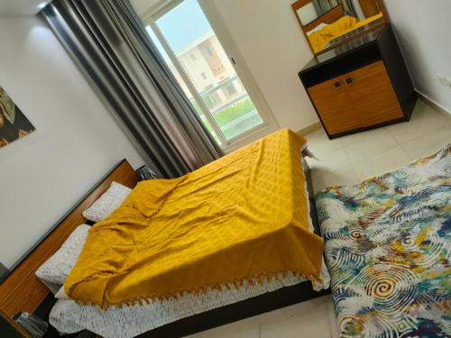 a bedroom with a bed with a yellow blanket and a window at قريه امواج الساحل الشمالي in El Alamein