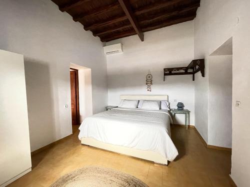 a bedroom with a white bed and a wooden ceiling at Finca Can Toni den Real in Sant Josep de sa Talaia
