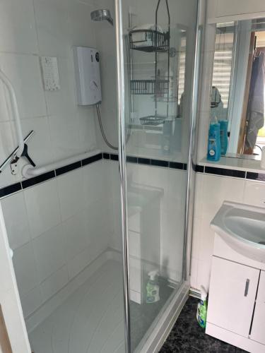 a shower with a glass door next to a sink at K109 Chalet in Camber