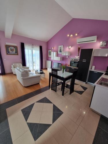 un soggiorno con pareti viola, tavolo e sedie di Kvarner Golden view Apartments a Matulji (Mattuglie)