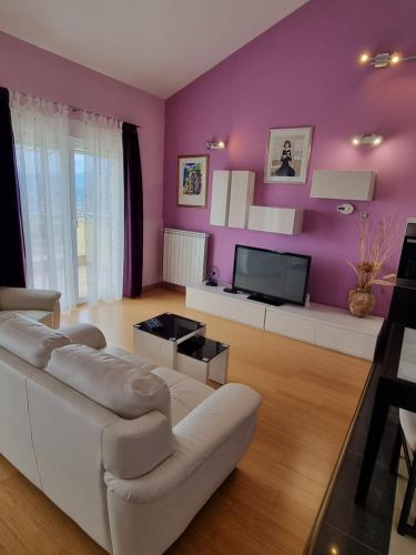 un soggiorno con divano bianco e parete viola di Kvarner Golden view Apartments a Matulji (Mattuglie)
