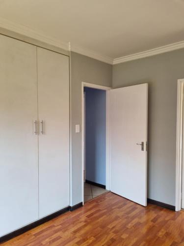 una stanza vuota con porte bianche e pavimenti in legno di Sunny Estate a Katlehong