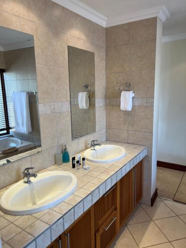 a bathroom with two sinks and a mirror at 211 Zebula in Mabula