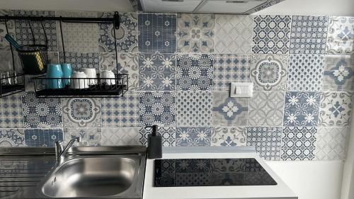 cocina con fregadero y pared de azulejos en ACCADEMIA Rooms, en Livorno