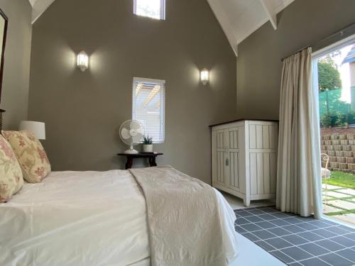 a bedroom with a white bed and a window at The Stables on Drew Avenue in Howick