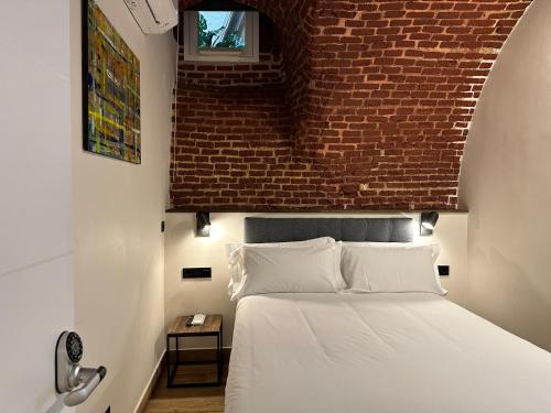 a bed in a room with a brick wall at PACOROOMS in Madrid