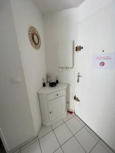 une salle de bain blanche avec un lavabo et un miroir dans l'établissement Appart cap D’agde, au Cap d'Agde