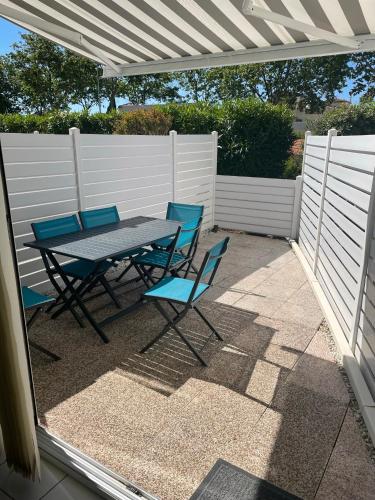 une table et des chaises sur une terrasse avec une clôture blanche dans l'établissement Appart cap D’agde, au Cap d'Agde