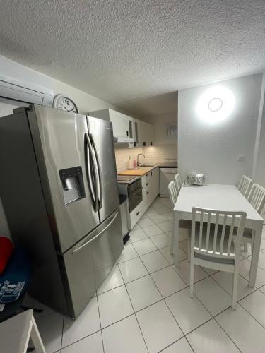 une cuisine avec une table et un réfrigérateur en acier inoxydable dans l'établissement Appart cap D’agde, au Cap d'Agde