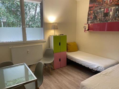 Cette petite chambre comprend un lit, un bureau et une table. dans l'établissement Appartement Mimosa, tram 2, parking, à Montpellier