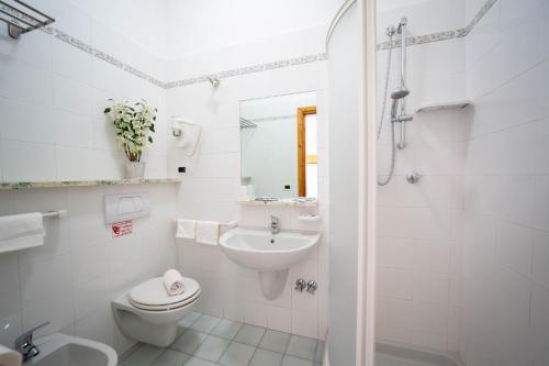 a white bathroom with a toilet and a sink at Hotel La Mandorla in Ischia