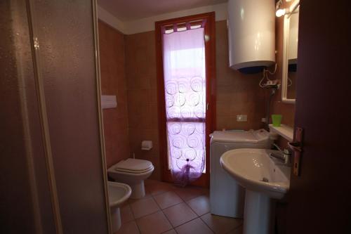 a bathroom with a toilet and a sink and a window at Terraced house with garden and porch in Rosolina Mare