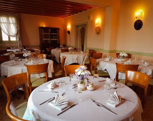 uma sala de jantar com mesas brancas e cadeiras com flores em Possessioni Ferraresi em Melara