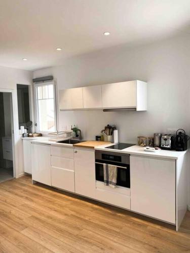 a kitchen with white appliances and a wooden floor at « Hortense » in Soorts-Hossegor