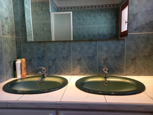 La salle de bains est pourvue d'un lavabo vert et d'un miroir. dans l'établissement 4 saisons, à Font-Romeu-Odeillo-Via