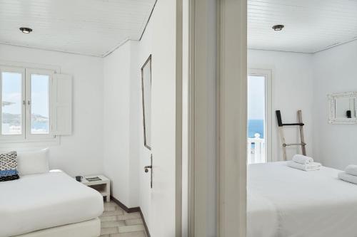 Dos camas en una habitación con paredes y ventanas blancas. en Boho Home Sea View by Monocle, en Mykonos ciudad