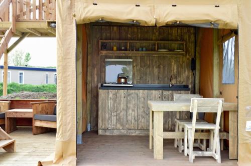 une table et des chaises sur une terrasse avec un mur en bois dans l'établissement Sahara Stay, à Vluchtenburg