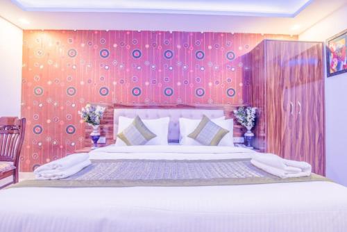 a bedroom with a large bed with a red wall at FabExpress Pearl Robe in New Delhi