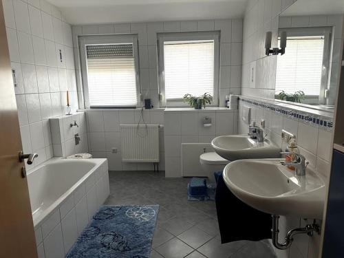 bagno con 2 lavandini, vasca e 2 servizi igienici di Schöne Ferienwohnung in der Fränkischen Schweiz 
