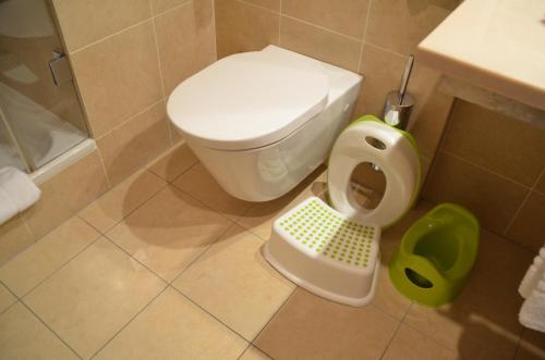a bathroom with a toilet and a green trash can at Hotel Clement in Prague