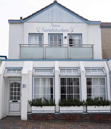 a white building with a sign on top of it at Haus Sandröschen in Norderney
