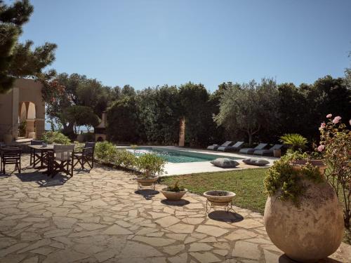 a patio with a table and chairs next to a pool at Villa Anatoli - Tranquil Escape with Scenic Views, by ZanteWize in Akrotiri