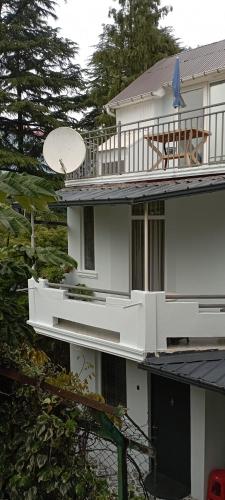 a white house with a balcony and trees at Guesthouse Next to beach in Batumi