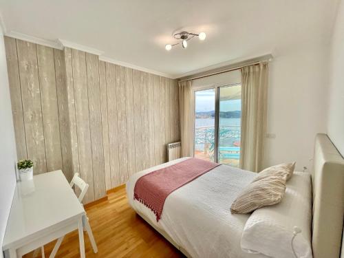 a bedroom with a bed and a table and a window at Casa Da Moura in Combarro