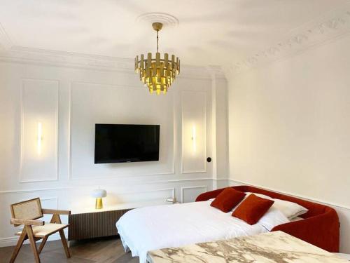 a bedroom with a bed and a television and a chandelier at Le petit Versailles - T2 au centre-ville in Grenoble