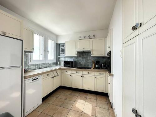 Il comprend une cuisine blanche avec des placards blancs et du carrelage. dans l'établissement Bord de mer vue panoramique avec parking privé, à Saint-Jean-de-Monts