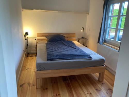 a bedroom with a bed with blue sheets on a wooden floor at Haus Käthe am Deich in Balje