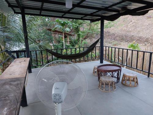 a porch with a fan and two tables and chairs at Thong Family Homestay Chiangdao in Chiang Dao