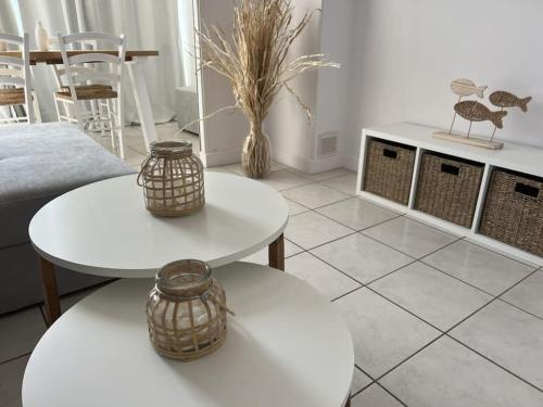 a living room with two white tables and chairs at Superbe T2 vue mer, clim, parking gratuit in Canet-en-Roussillon