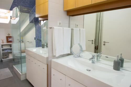 a white bathroom with a sink and a mirror at Lousã Varandas House in Lousã