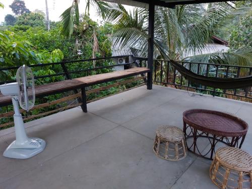 a porch with a bench and two chairs and a fan at Thong Family Homestay Chiangdao in Chiang Dao