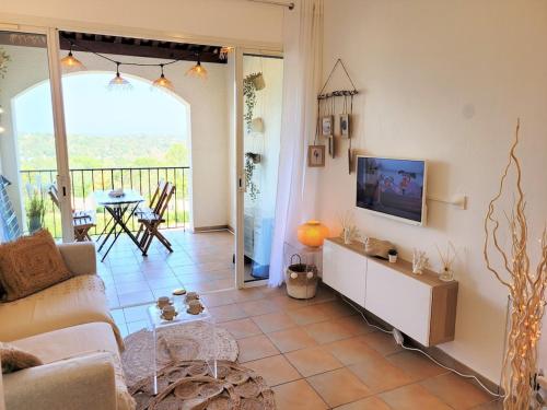 un salon avec un canapé et une télévision dans l'établissement Vue mer et clim Les Restanques coquelicots 1115, à Grimaud