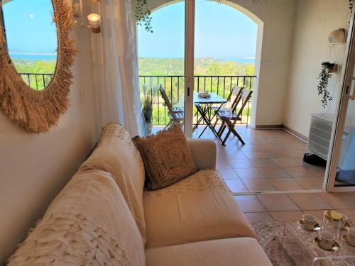 d'un salon avec un canapé et d'un balcon avec une table. dans l'établissement Vue mer et clim Les Restanques coquelicots 1115, à Grimaud