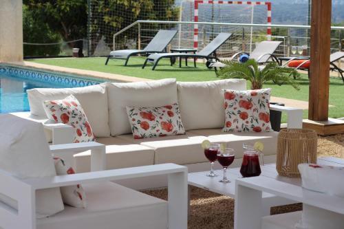 a white couch sitting next to a pool with glasses of wine at Casa Rancho Grande in Jávea