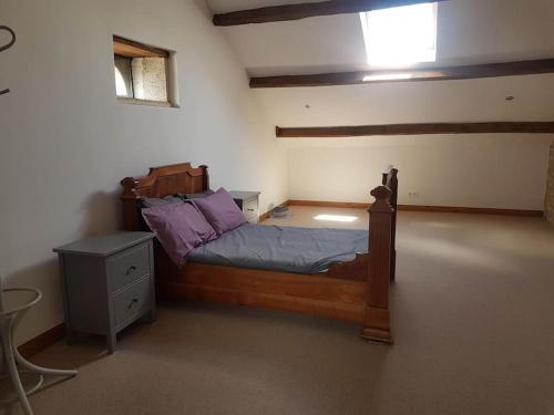- une chambre avec un lit en bois et des oreillers violets dans l'établissement Maison Aunac, à Aunac