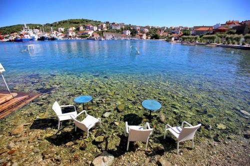 a group of chairs and tables in the water at Studio apartments Kali in Kali